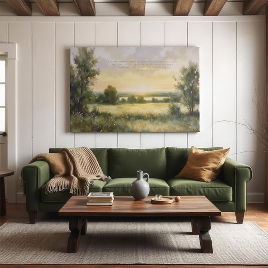 Cozy living room with a green sofa, wooden coffee table, and natural light. A large canvas of Psalm 143:8 with a peaceful landscape of rolling fields and trees at sunrise adds a serene touch to the space.
