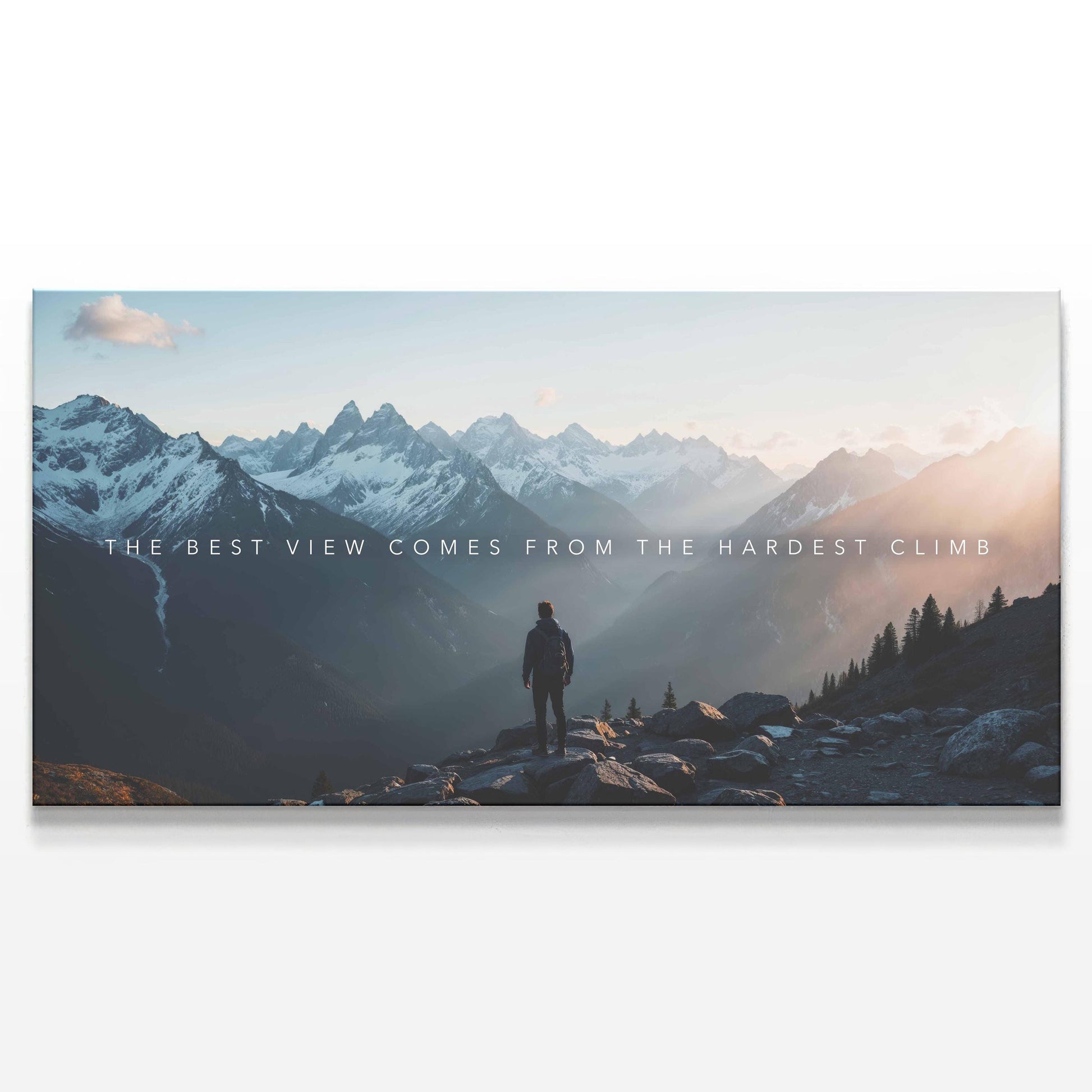 A motivational mountain landscape canvas print featuring a lone hiker standing atop a rugged peak, overlooking a breathtaking sunrise-lit valley. The phrase &quot;The best view comes from the hardest climb&quot; is subtly overlaid, inspiring perseverance and resilience. This adventure-inspired wall art is perfect for offices, gyms, or modern home decor, adding a bold and encouraging statement.