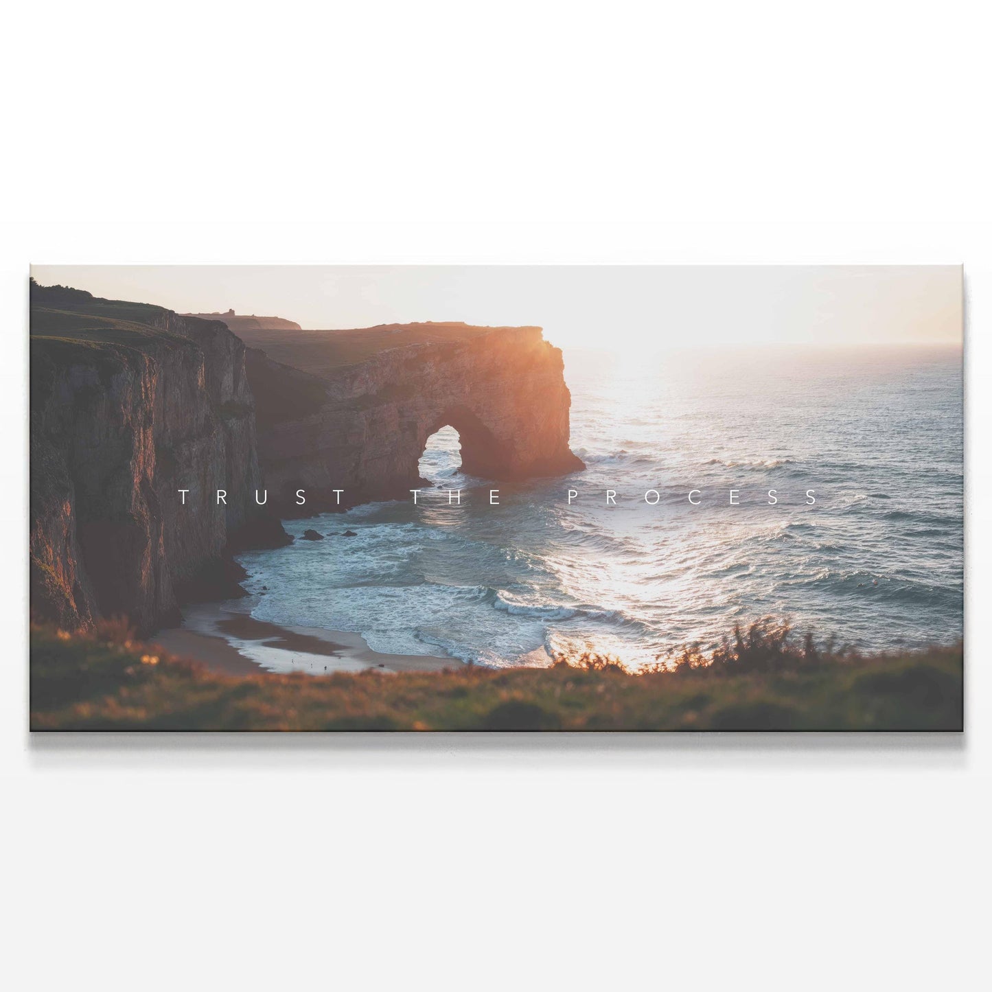 A detailed view of the canvas print featuring a majestic coastal cliff and ocean waves under the golden light of sunset. The phrase &quot;Trust the Process&quot; is subtly overlaid across the scene. The artwork has a tranquil yet powerful aesthetic, making it ideal for offices, living rooms, or modern interiors. The neutral tones and natural scenery evoke peace, perseverance, and reflection.