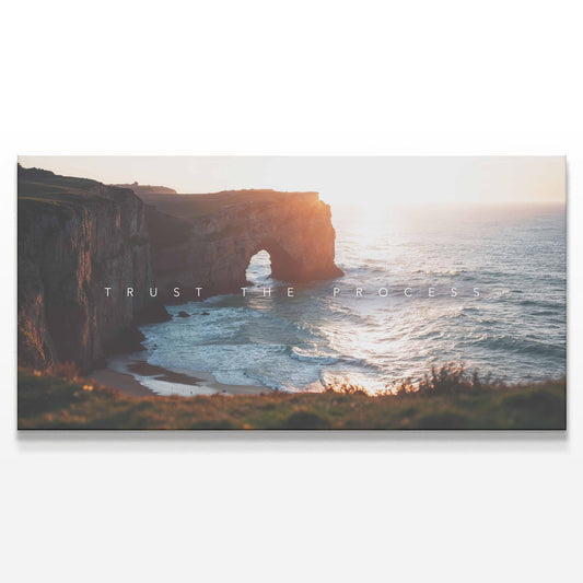 A detailed view of the canvas print featuring a majestic coastal cliff and ocean waves under the golden light of sunset. The phrase &quot;Trust the Process&quot; is subtly overlaid across the scene. The artwork has a tranquil yet powerful aesthetic, making it ideal for offices, living rooms, or modern interiors. The neutral tones and natural scenery evoke peace, perseverance, and reflection.