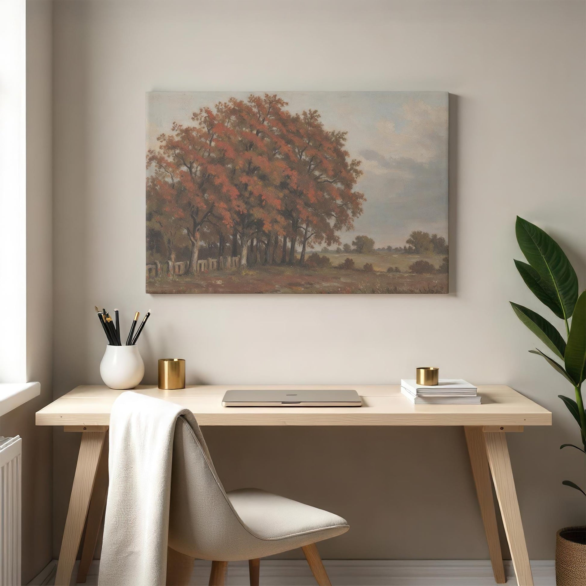 Cozy home office featuring an autumn landscape canvas above a wooden desk. Styled with minimalist decor, gold accents, and a neutral palette for a warm and productive workspace.