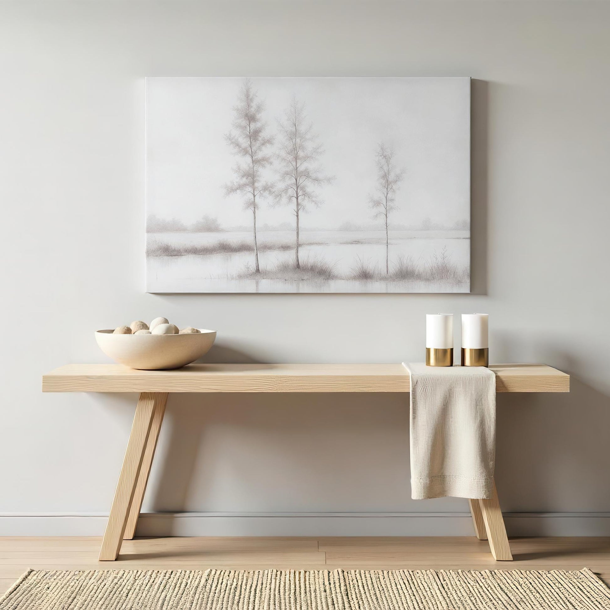 A minimalist console table with modern decor, centered beneath a large grayscale tree landscape canvas. The soft, neutral tones enhance a tranquil, elegant space ideal for contemporary home styling.