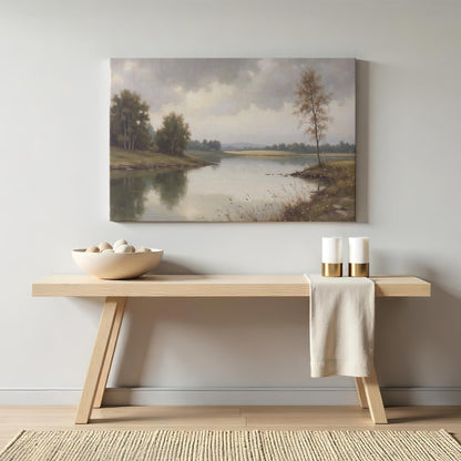 A cozy home interior setting featuring the framed lake landscape canvas above a minimalist wooden console table. The decor includes neutral-colored accents like a woven basket, candles, and soft textiles.