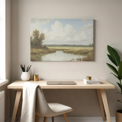 A peaceful countryside landscape canvas featuring a reflective river, lush greenery, and a soft blue sky, mounted above a minimalist wooden desk. The scene is styled with a modern chair, gold-accented decor, and a potted plant.