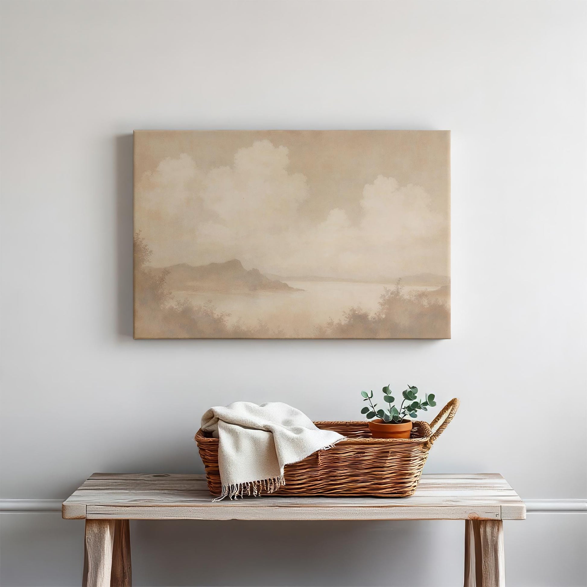 Soft, vintage-style lake landscape canvas print in warm earth tones. Displayed above a wooden bench with a woven basket and greenery, adding a cozy rustic charm to the space.