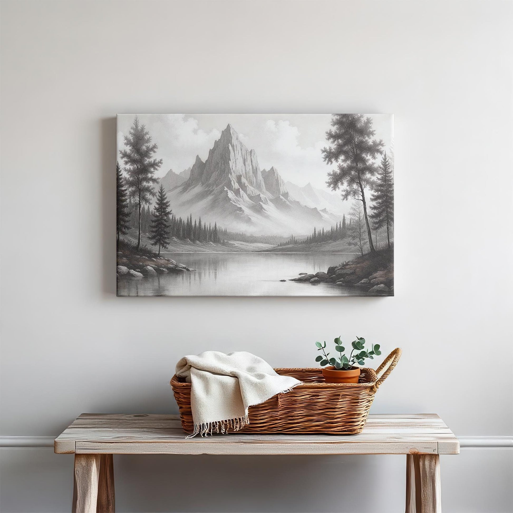 Black and white mountain landscape canvas wall art above a rustic wooden entryway table with a woven basket, cozy throw blanket, and potted plant, creating a warm and inviting farmhouse-inspired decor setting.
