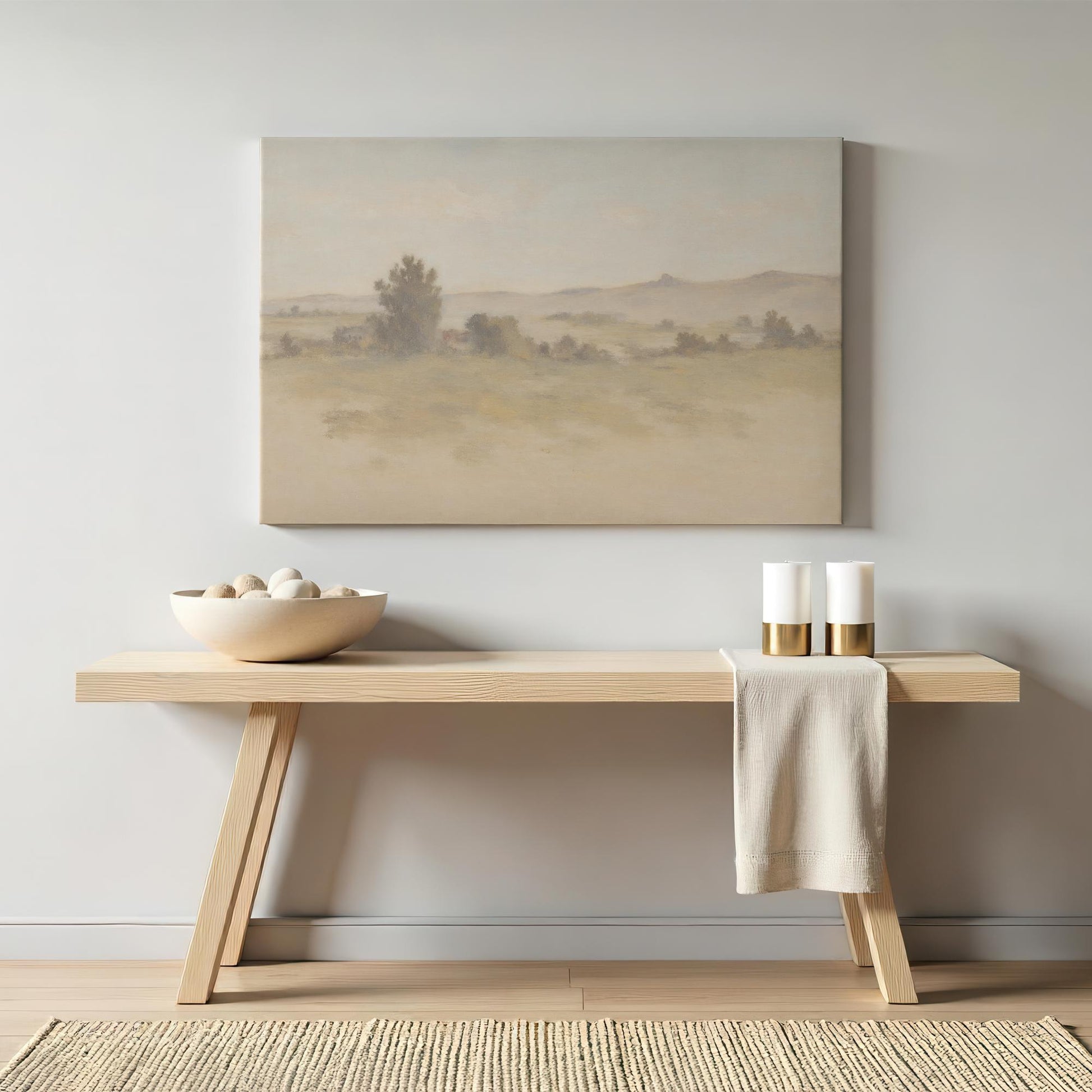 A contemporary entryway with a sleek wooden console table, decorated with neutral accessories and a soft landscape canvas print. The warm, earthy hues of the art complement the minimalist decor and natural wood tones.