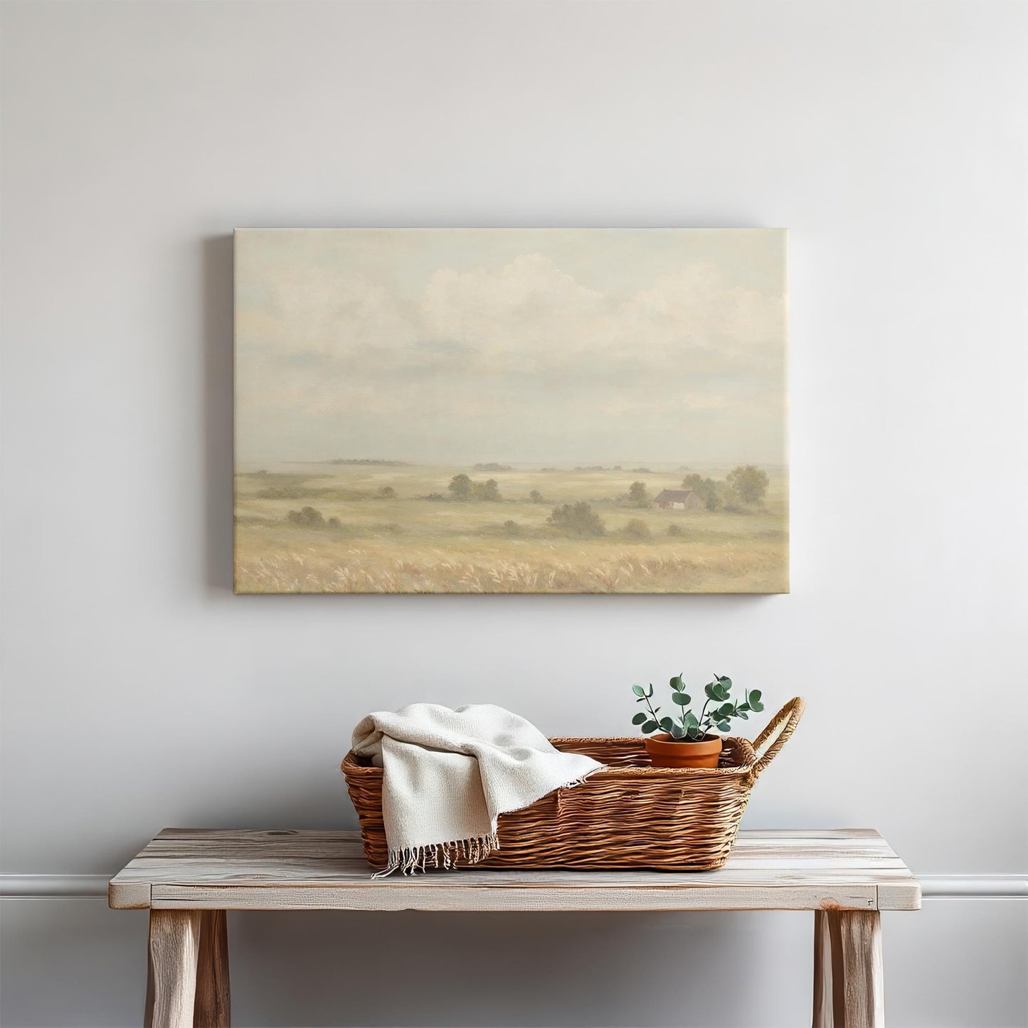 Large neutral landscape canvas print hanging above a wooden entryway table with a woven basket and potted plant. Elegant farmhouse wall decor for cozy home styling.