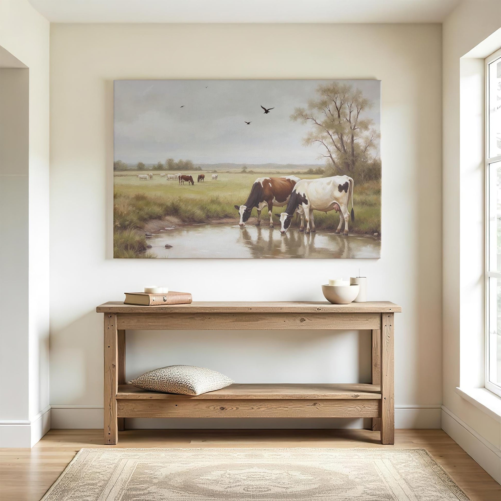 A minimalist entryway with a natural wood console table, soft lighting, and a serene canvas painting of cows near water. Neutral decor and a calming color palette create a welcoming country-inspired atmosphere.