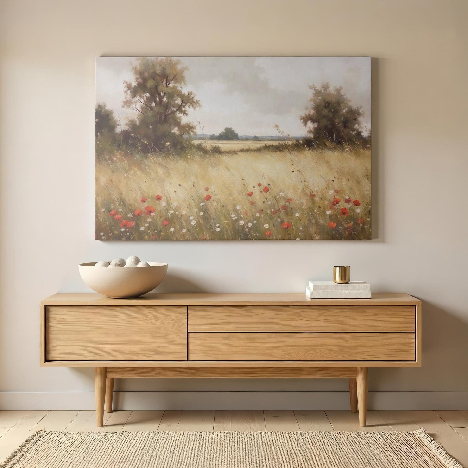Modern living space with a wooden console table featuring, gold-accented decor, and stacked books. Above hangs a gallery-wrapped canvas titled &#39;Golden Meadow,&#39; showcasing a vibrant wildflower and poppy field in a serene landscape.