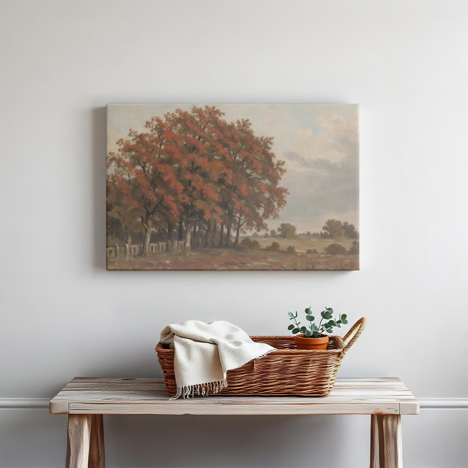 Rustic autumn landscape canvas wall art above a wooden console table. Styled with a woven basket, cozy throw blanket, and potted greenery for a warm, inviting touch. Perfect for farmhouse, vintage, or traditional decor.
