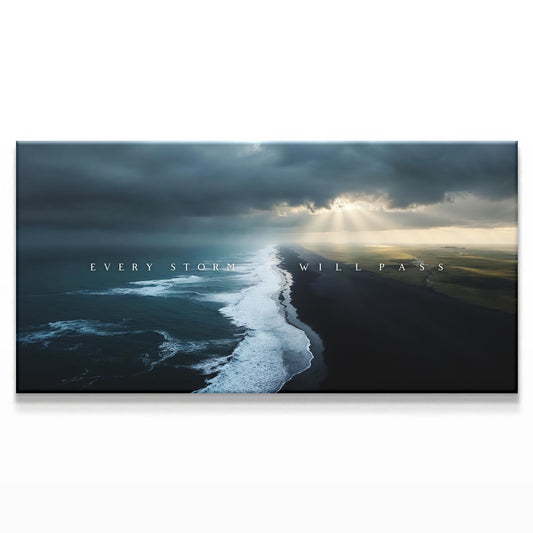 A coastal view with dark, turbulent waves crashing against a black sand beach. The stormy sky on the left fades into a calmer, brighter scene on the right, where the sunlight peeks through the clouds, illuminating the beach and giving hope.