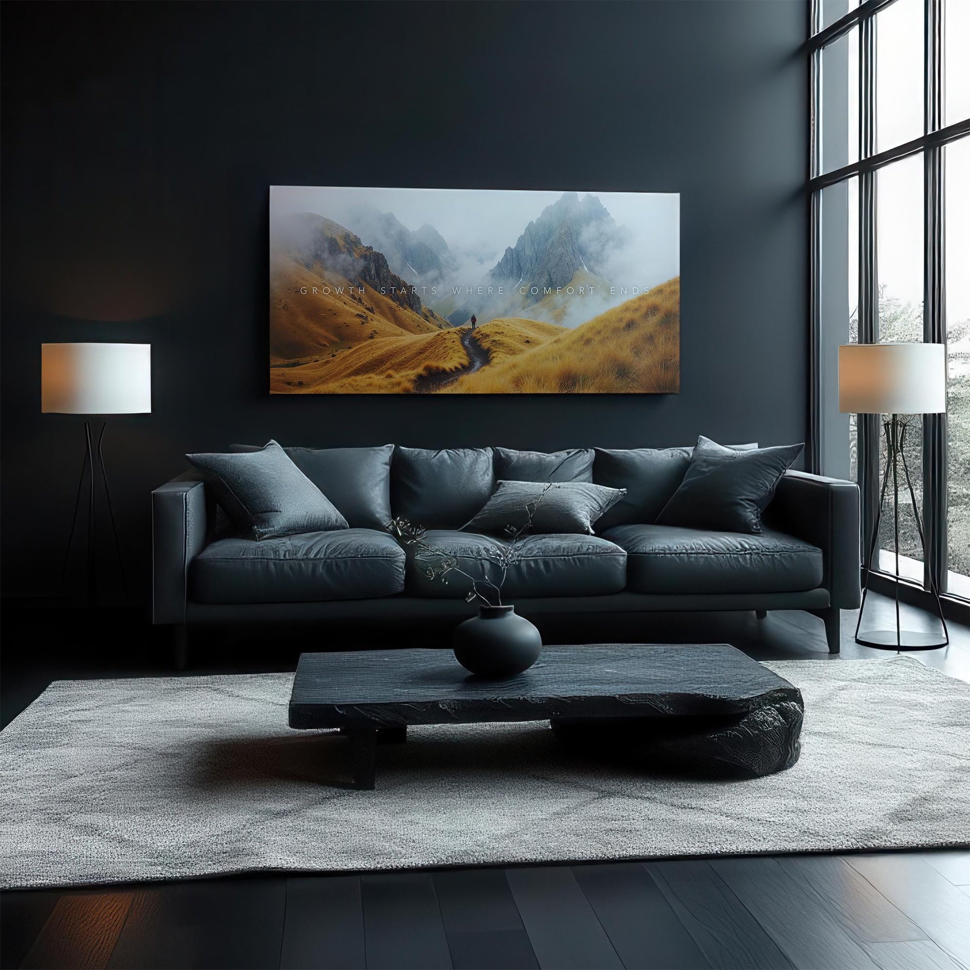 A cozy, contemporary living room featuring a black sofa and dark wooden furniture. The &quot;Growth Starts Where Comfort Ends&quot; canvas is displayed above the couch, adding an inspiring touch to the space. Large windows let natural light brighten the room.