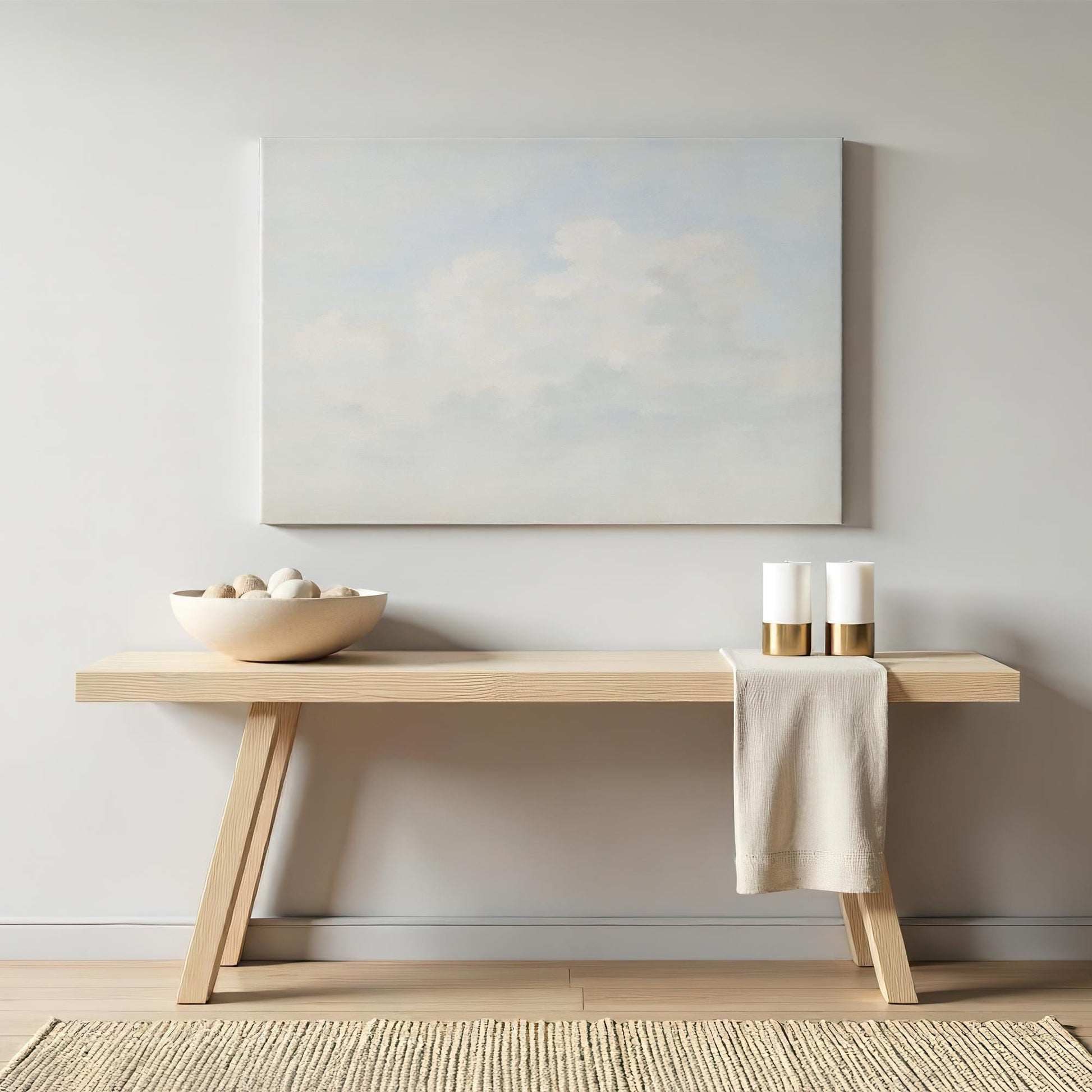 Soft cloud painting canvas displayed above a modern wooden console table. Styled with neutral decor and gold-accented candles for an elegant, airy aesthetic.