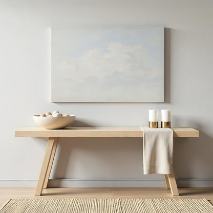 Soft cloud painting canvas displayed above a modern wooden console table. Styled with neutral decor and gold-accented candles for an elegant, airy aesthetic.