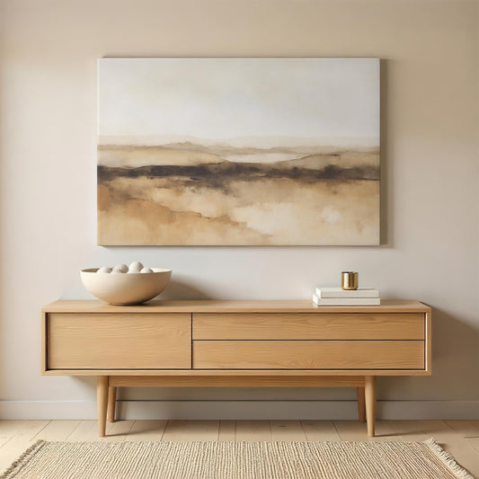 A modern living space featuring a large abstract desert landscape canvas in neutral tones above a wooden console table. Minimalist decor with a ceramic bowl and gold accents enhances the serene ambiance.