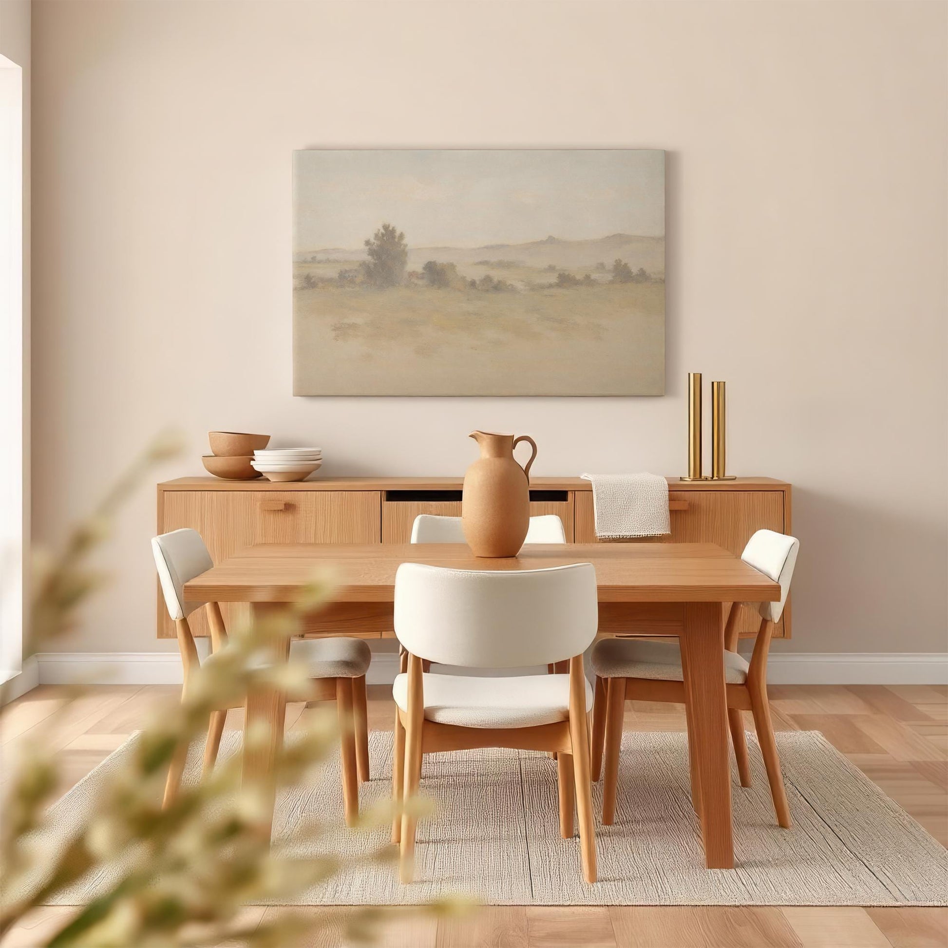 A cozy dining room with a rustic wood table and matching sideboard, featuring a large canvas print of a tranquil countryside landscape. Earthy tones and minimalist decor create a warm, inviting atmosphere.