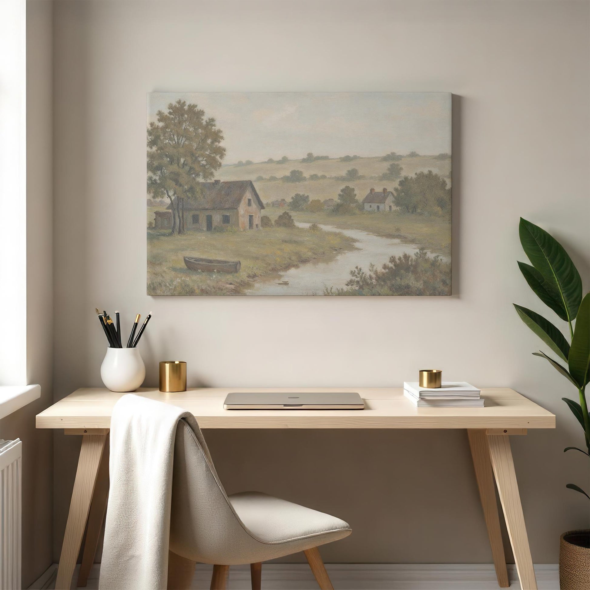 A modern minimalist workspace with a light wood desk, white chair, and a green plant, complemented by a vintage countryside landscape canvas featuring a peaceful river, rustic home, and rolling green hills in soft muted tones.