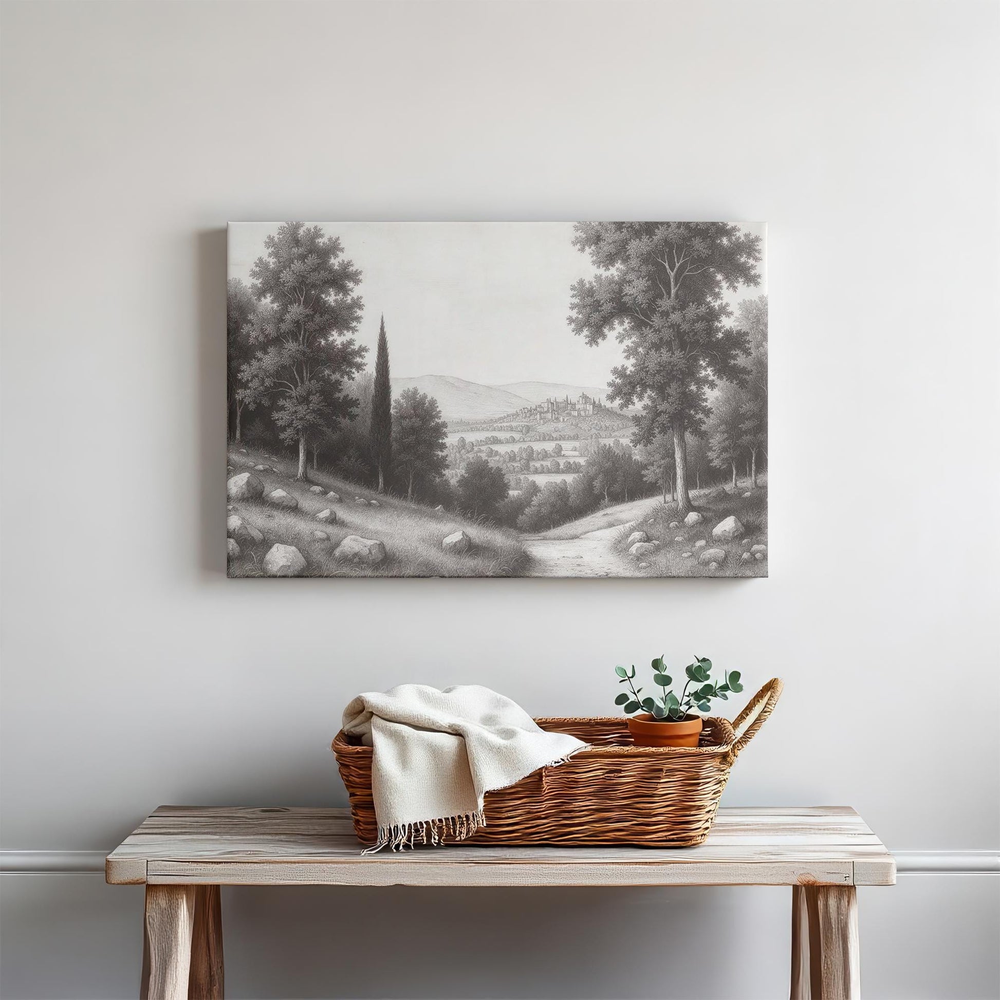 Rustic bench decor with a woven basket, cozy blanket, and greenery, complemented by a black and white landscape canvas featuring a serene countryside path.