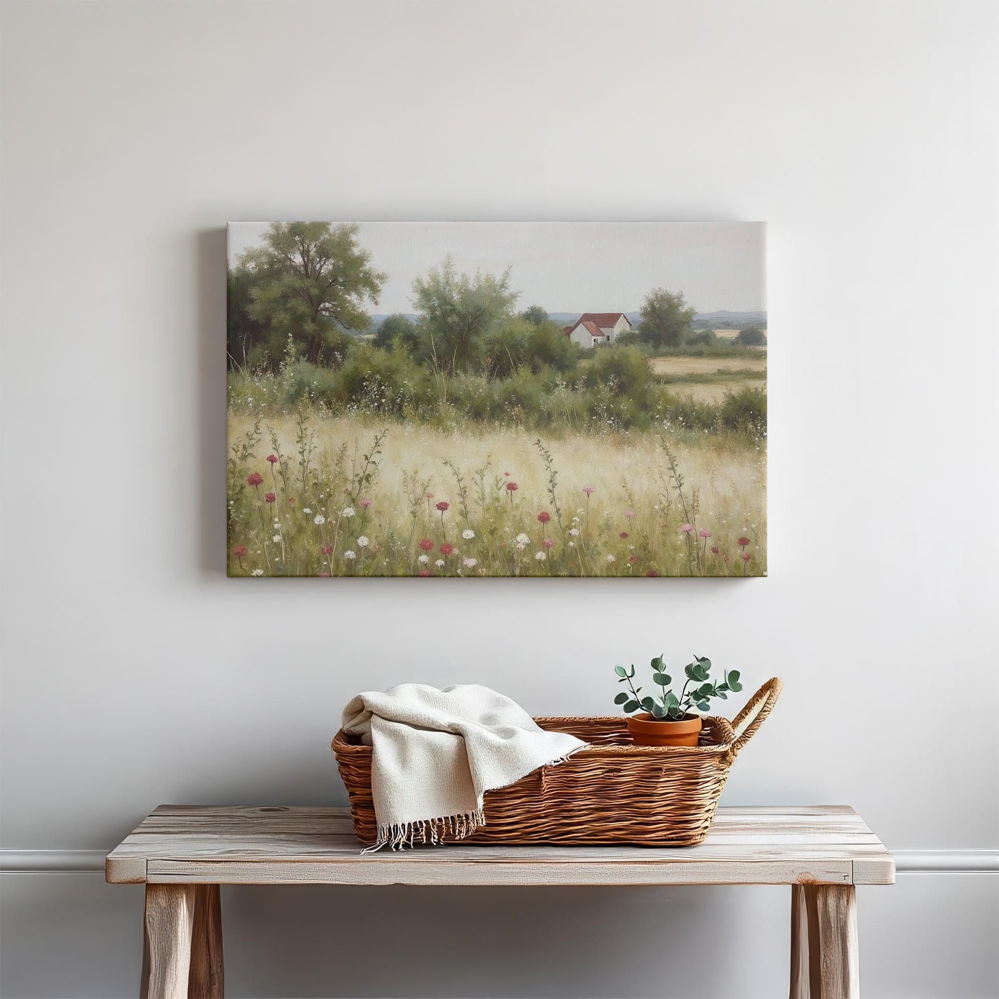 Rustic countryside canvas print with delicate wildflowers and a distant home, styled in a modern farmhouse entryway with a wooden console table, woven basket, and minimalist decor.