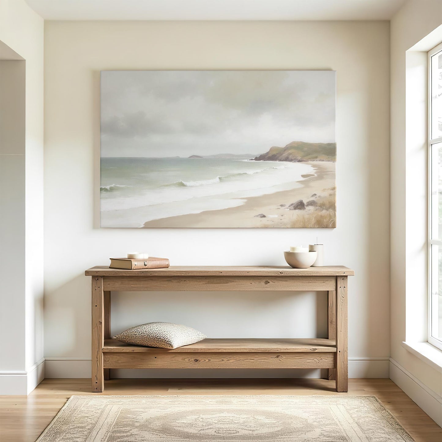 Minimalist entryway with coastal wall art above rustic wooden console table. Natural light highlights the serene beach painting, paired with neutral decor, ceramic bowls, and cozy textures for a warm welcome.