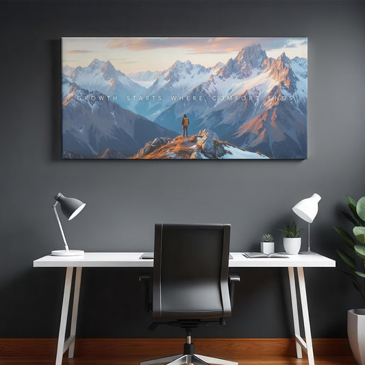A modern office with a sleek white desk and black ergonomic chair. The mountain canvas hangs on the wall, showcasing a vast mountain range at sunset. Soft lighting fills the space, with no harsh shadows.