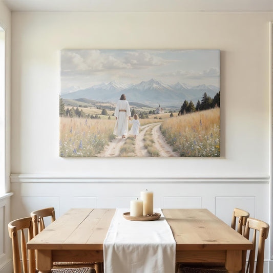 A minimalist dining room with a rustic wooden table, candles, and a basket. Above the table hangs a canvas of Jesus and a child walking along a scenic mountain path. The peaceful, natural landscape creates a calm, spiritual atmosphere in the space.