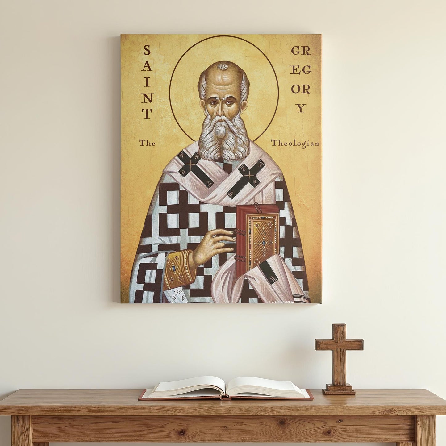 Saint Gregory icon mounted on a simple white wall above a wooden prayer table with an open book and small cross. The minimalist background highlights the icon’s traditional colors, detailed patterns, and calm, theological presence.