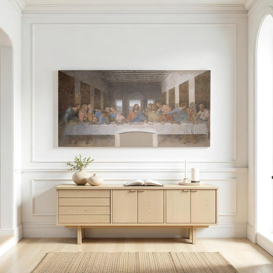 A bright, sophisticated living space featuring a The Last Supper canvas print above a light wood console table. White walls, soft natural light, and neutral decor create a timeless and serene atmosphere, making this a perfect religious centerpiece for a living room, dining area, or church setting. The muted tones of the artwork complement modern, farmhouse, and classic interiors.