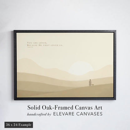 Minimalist Christian nursery art featuring the Bible verse &#39;You are loved, because He first loved us&#39; from 1 John 4:19. Set against soft beige rolling hills and a glowing sun, the solid oak black floater frame enhances the peaceful tone. A perfect piece of scripture wall art for nurseries, baby rooms, or spiritual home decor.