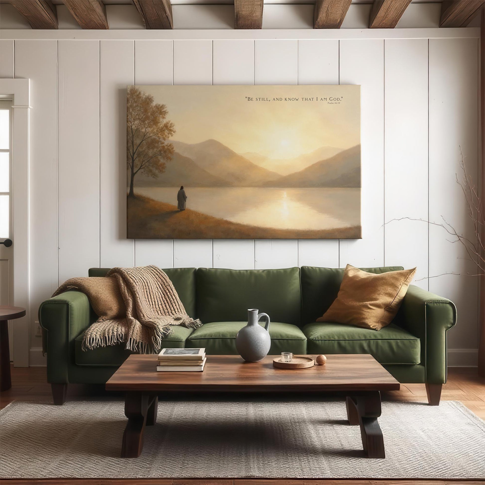 Large scripture canvas print displayed above a cozy green couch in a modern farmhouse living room; features Jesus by a tranquil lake at sunset with Psalm 46:10 text reading &quot;Be still, and know that I am God&quot; — a perfect statement piece for Christian home decor.