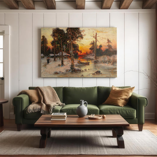A large canvas print of Julius von Klever&#39;s Returning Home at Sunset displayed in a cozy, neutral-toned living room above a green velvet couch. The artwork features a tranquil winter forest scene with a glowing sunset reflecting off icy water, pine trees casting long shadows, and a figure heading toward a quiet homestead. The richly colored canvas adds warmth and old-world elegance to any space, ideal for rustic or classic interiors.
