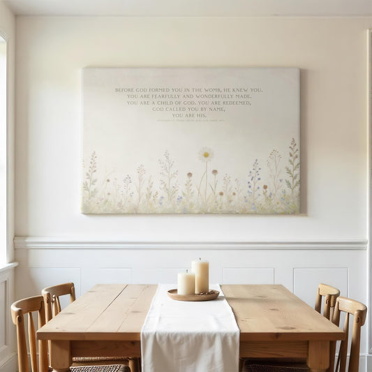 Framed Christian canvas art hung above a dining table, featuring a soft watercolor floral field and inspirational Bible verses. Perfect for farmhouse decor or a peaceful family dining space, this artwork blends modern minimalism with faith-centered scripture, including Psalm 139:14 and Jeremiah 1:5.